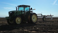 a green tractor in a plowed field