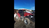 a red tractor parked in a dirt lot