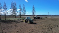 a tractor plowing a field with trees in the background