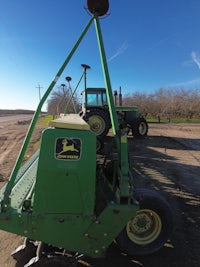 a green tractor parked on a dirt road