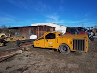 a yellow truck is parked in a dirt lot